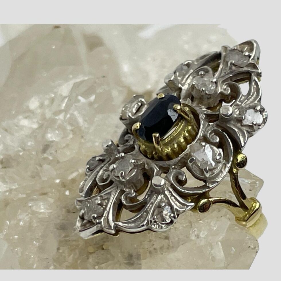 Close up of Edwardian sapphire diamonds ring in close up and seen with ring front facing top left corner. The old rose cut diamonds catch the light and sparkle.