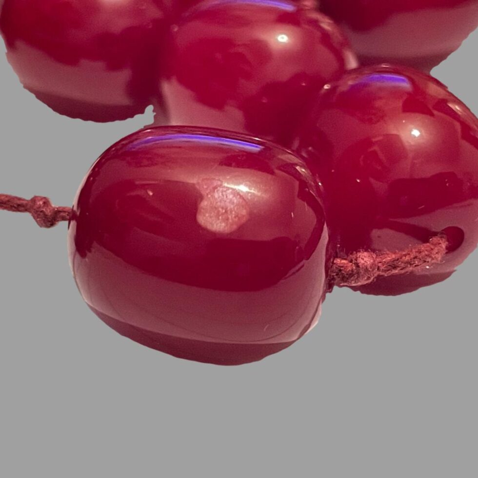 A close up photo of the scuffed cherry amber bakelite bead.