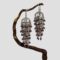 Main photo of silver garnet chandelier earrings displayed hanging from a twig of cherry tree. The twig bends upward so the earrings are not on the level with left one slightly lower than the right. The articulated design means these earrings move with your movement and always the right way round! The earrings have been called chandelier because of the way they hang but they could also be described as flapper dress and would actually make great accessories for a 1920s them look. The garnets are a beautiful shade of deep pink with a purple hew - like red grapes but tinier!