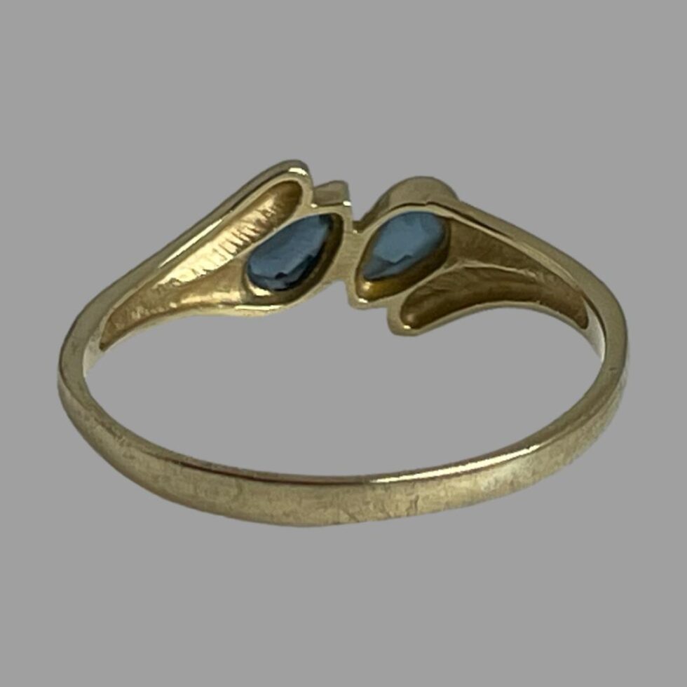 Photo of the gold blue gemstone ring displayed from the back showing the setting for the blue gemstones and the unusual design at the front.