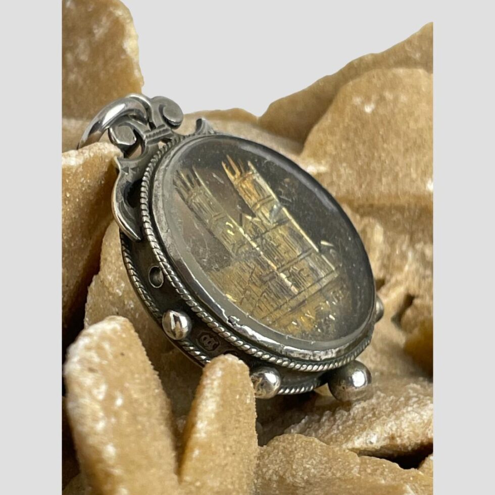Photo of Westminster Abbey fob still displayed on the rock of desert sand rose this time seen from a side angle with the front of fob facing upwards towards the top right corner.
