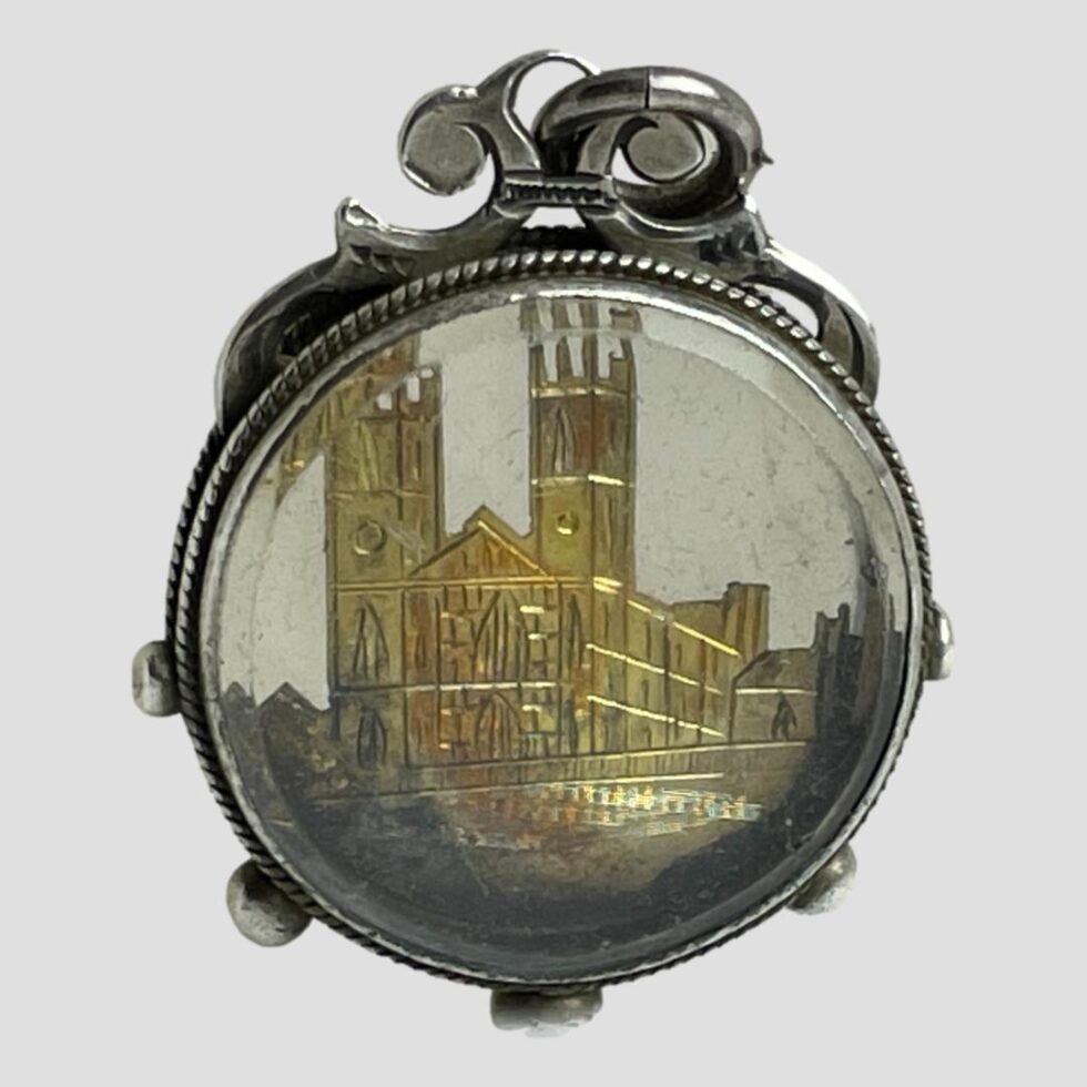Photo of Victorian Westminster souvenir fob displayed against a plain light grey background with the reverse side to lettered side on display. This is the exact same as the front without the lettering below.
