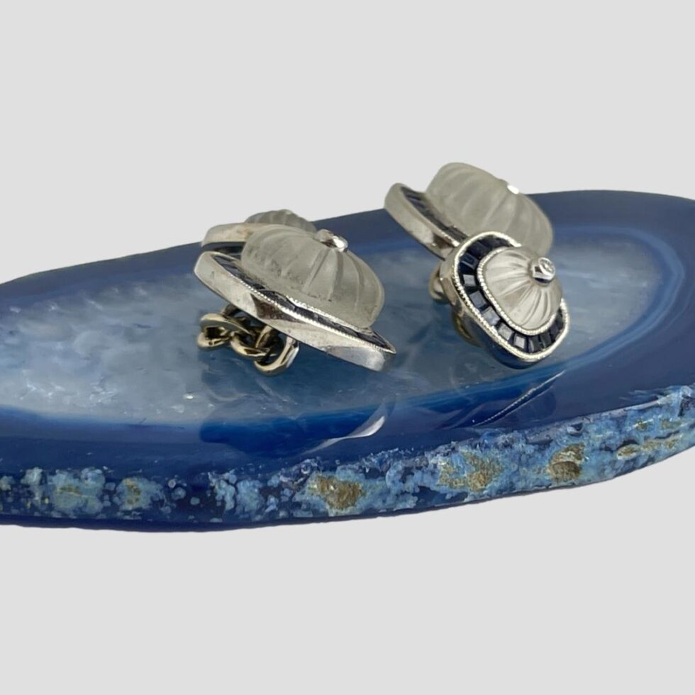 Photo of both cufflinks displayed outside of the box and displayed on top of a small slice of blue agate. We are looking at the cufflinks from mostly a side angle to show the depth.