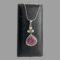 Main photo of ruby sapphire pendant &chain displayed hanging from the back of an old jewellery box. The chain has been wound round the box to secure the necklace and pendant in place. The main focus of this piece is without question the pendant. The carved ruby is a deep pink-almost cerise in colour and beautifully carved into a flower which covers the whole space. Around the floral ruby is a frame of silver with an outer edge of multiple coloured sapphires which include pink, blue, yellow, white and these enhance the floral ruby further. Above the ruby flower and multi coloured sapphire area is a bail separated section of 3 pearls (one at top and 2 below in a triangular formation) with a single pink sapphire at the centre. Above this is the generously sized large bail. The snake chain is suitable for this pendant and holds the weight well.