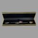 Main photo of the pair silver pickle forks displayed inside their case with the thistle ends at right and prongs at left. The fitted box holds the forks lengthways with a crossover section in the middle with one forks prongs and other forks thistle tip at centre. The box is not original to the forks but works very well.