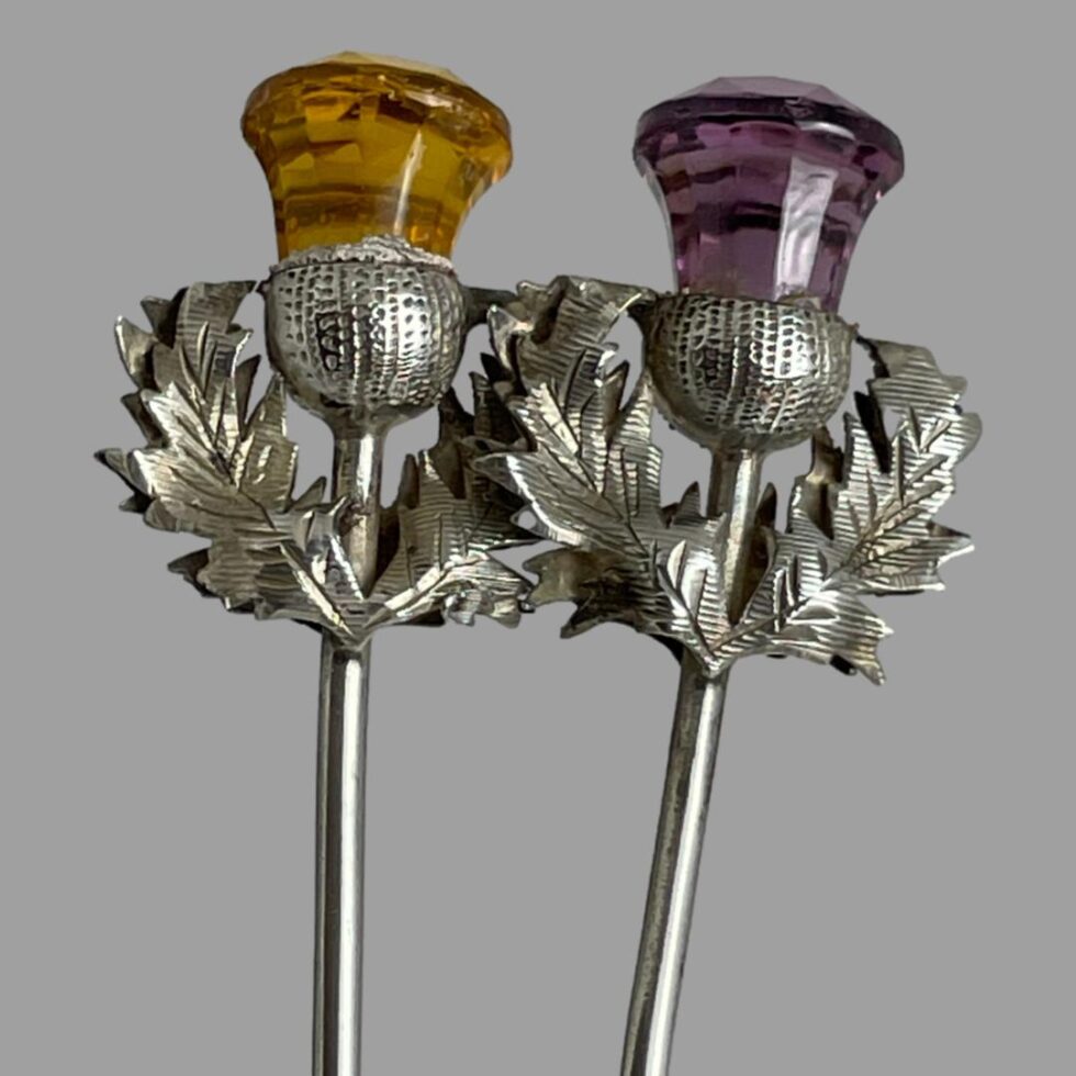 Close up photo of both the thistle heads - amber glass on left and purple on right.