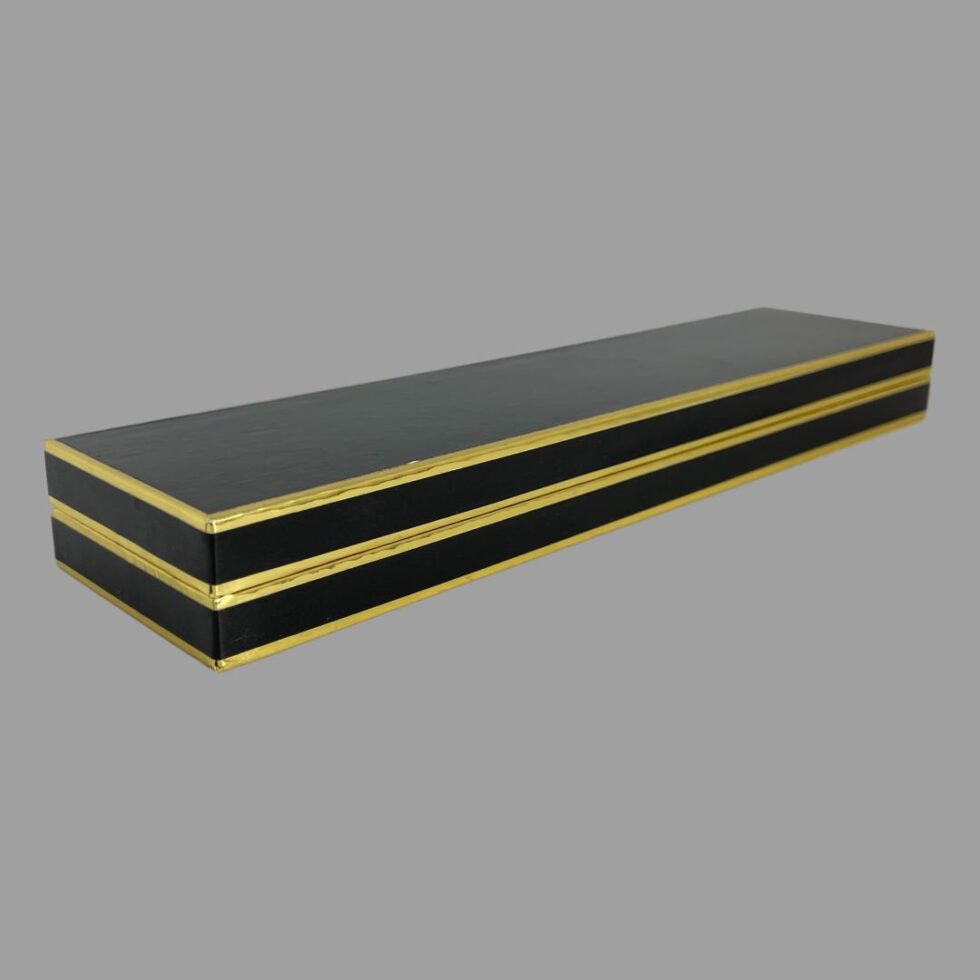 A photo of the closed box displayed diagonally across page. The box is black with gold edging.