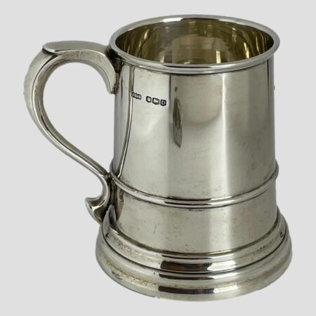 Main photo of silver half pint tankard displayed with the handle on the left and the full hallmark visible on the top right of handle. The tankard is slightly flared at the base making it a sturdy holder of your favourite beer, ale, stout or cider even. The tankard is in very good condition with no damage - almost like it has never been used. Lovely gift item to someone who'll appreciate quality or, as a gift to yourself!