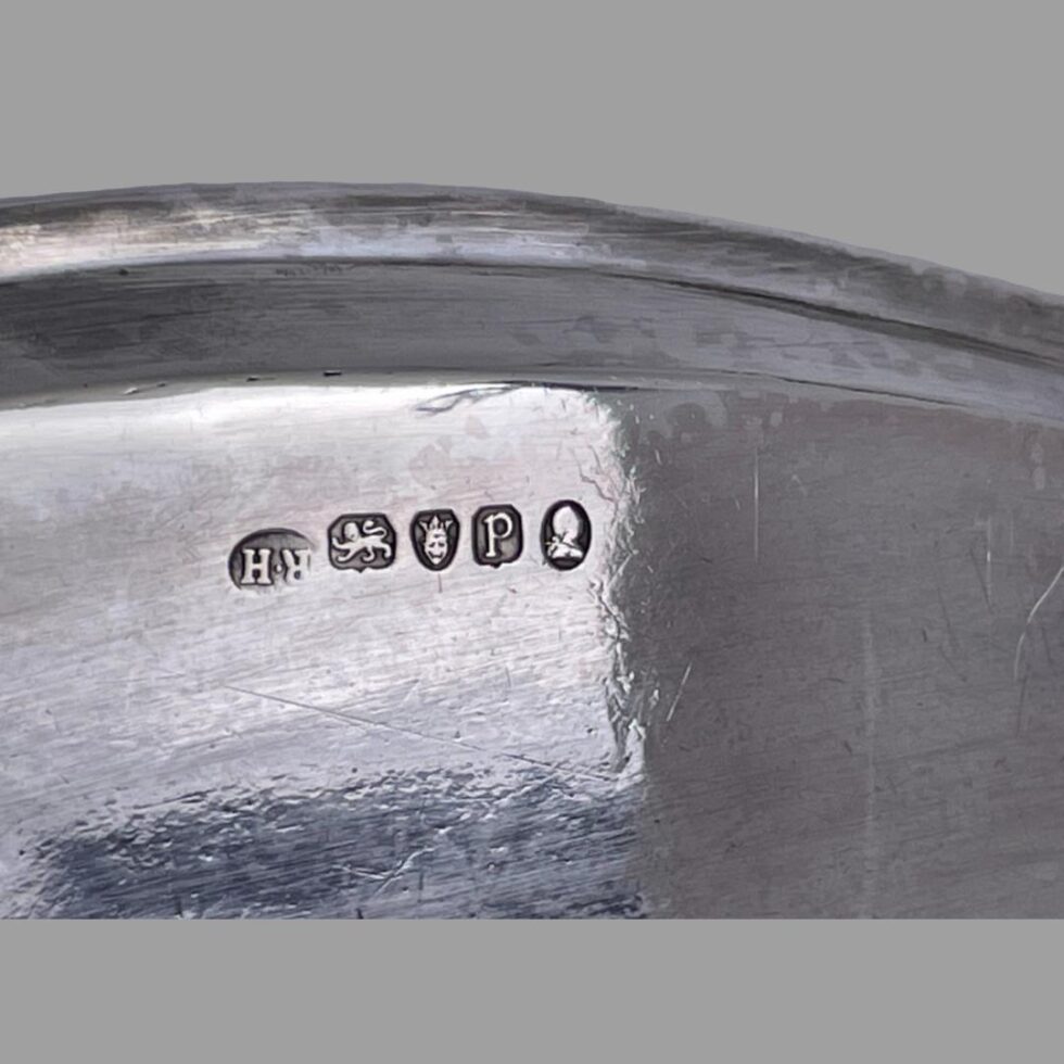 Close up photo of the full hallmark on the base of the tray with assay office initials R. H. shown upside down from the hallmark.