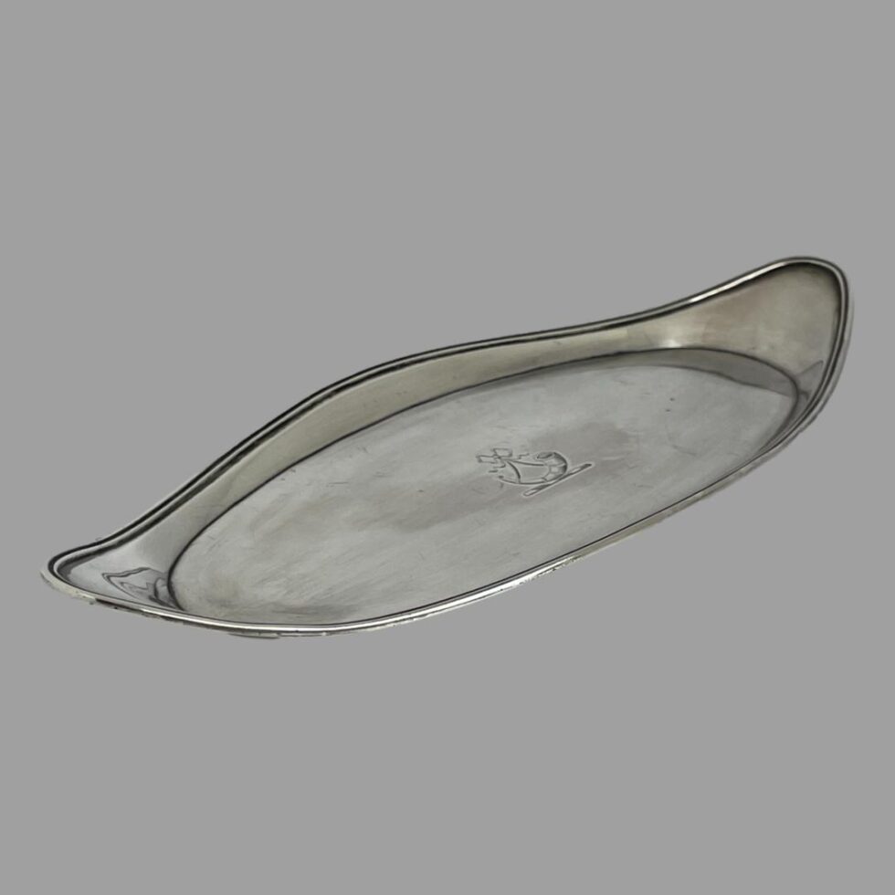 Photo of the George III snuffer tray displayed flat on its base and shown diagonally across the page with one tip in the bottom left corner and other in top right.