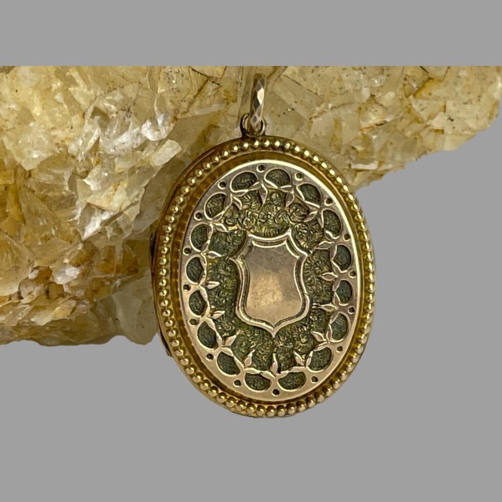Close up photo of the front of antique gold overlay locket showing the intricate design detail.