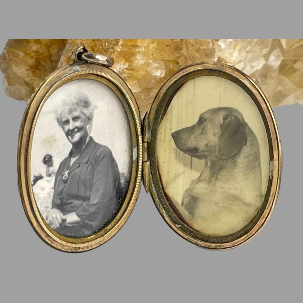 Photo of locket displayed upright and open with image of an elderly lady to the left and a dog in profile on the right both in black and white.