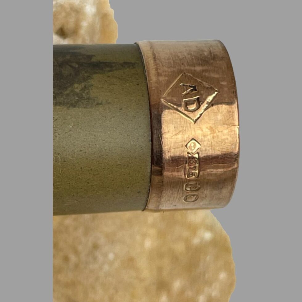 Close up photo of the gold tipped rim with makers mark AD and fully hallmark on display. The dark patch of the Bakelite just below the rim is partially visible.
