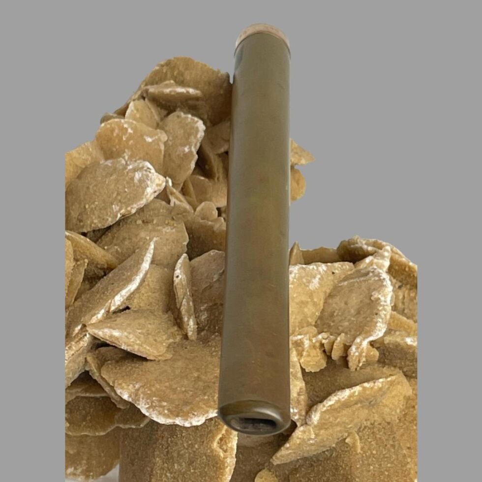 Photo of gold rimmed cigarette holder still displayed on the rock of natural desert rose this time with the flat mouth end in the foreground.