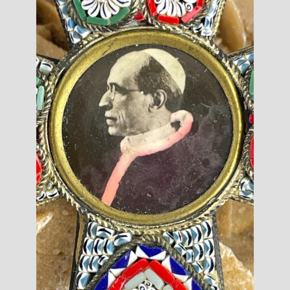 Close up photo of Pope Pius XII at the centre of the cross inside an open locket style brass setting.