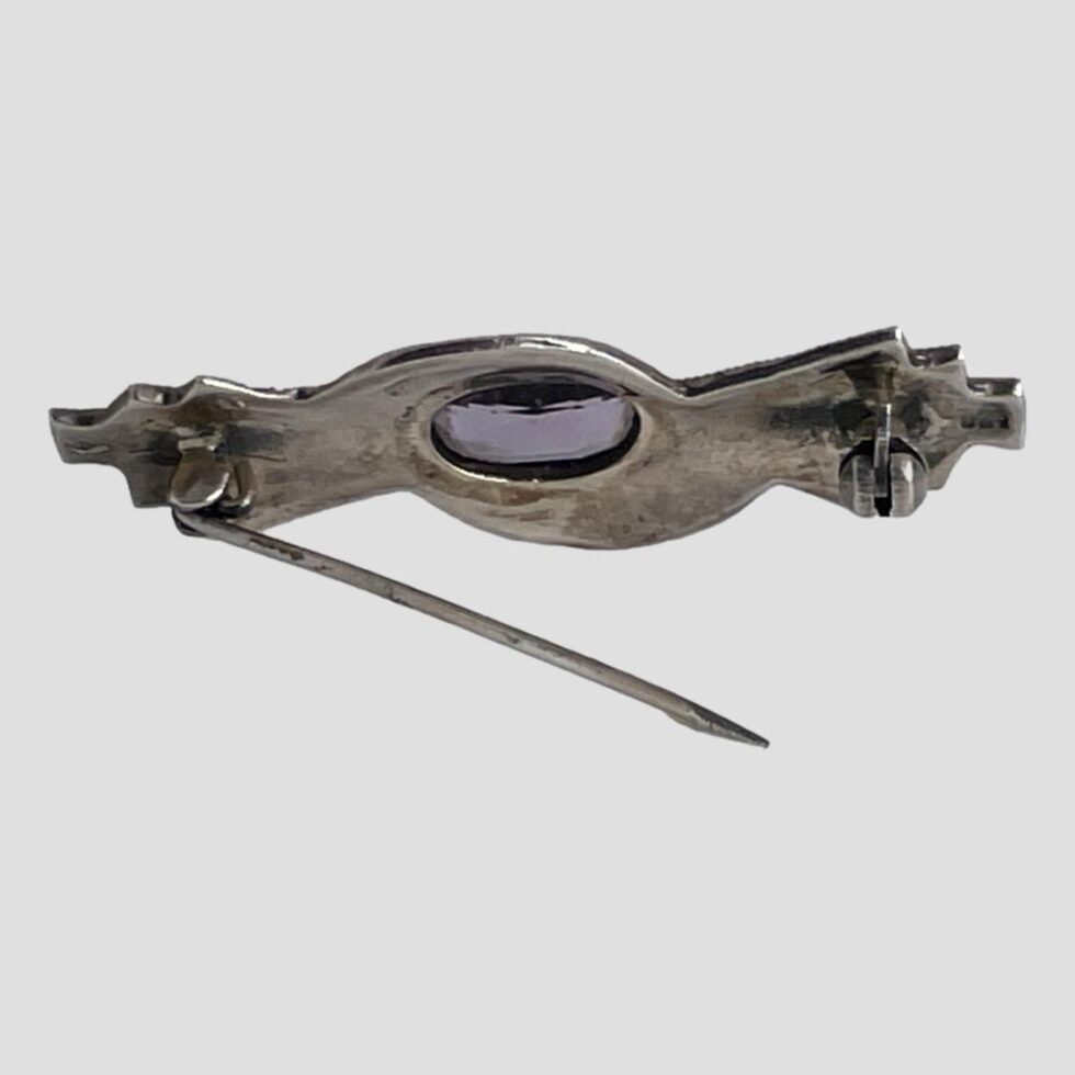 Photo of the back of the brooch which is displayed propped upright by its own pin.