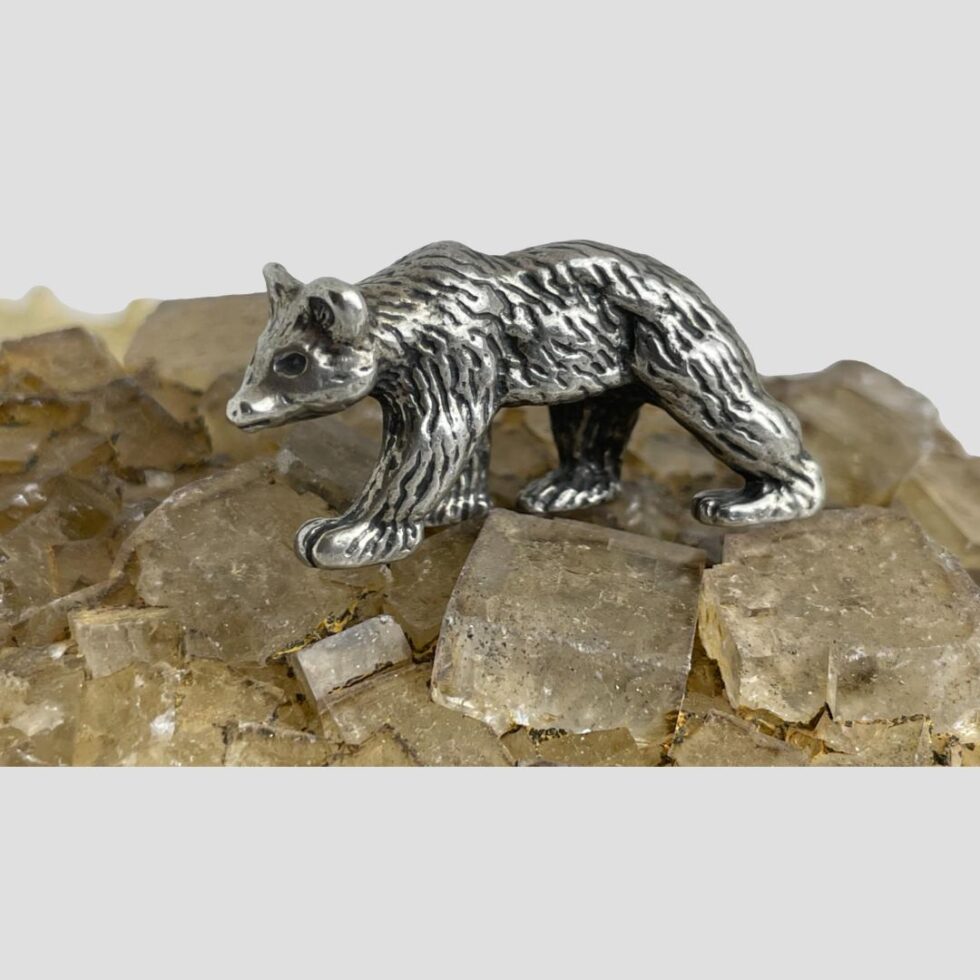 Photo of miniature silver bear this time facing to the left and the whole left side of body on display. It is still on top of the river quartz rock.