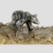 Main photo of miniature sterling silver bear displayed on top of a rock of natural river quartz with the bear facing toward bottom right corner. The whole righthand side of the bear is visible. The way it has been created makes the bear appear to be in motion. Rather a fabulous piece with good detail.