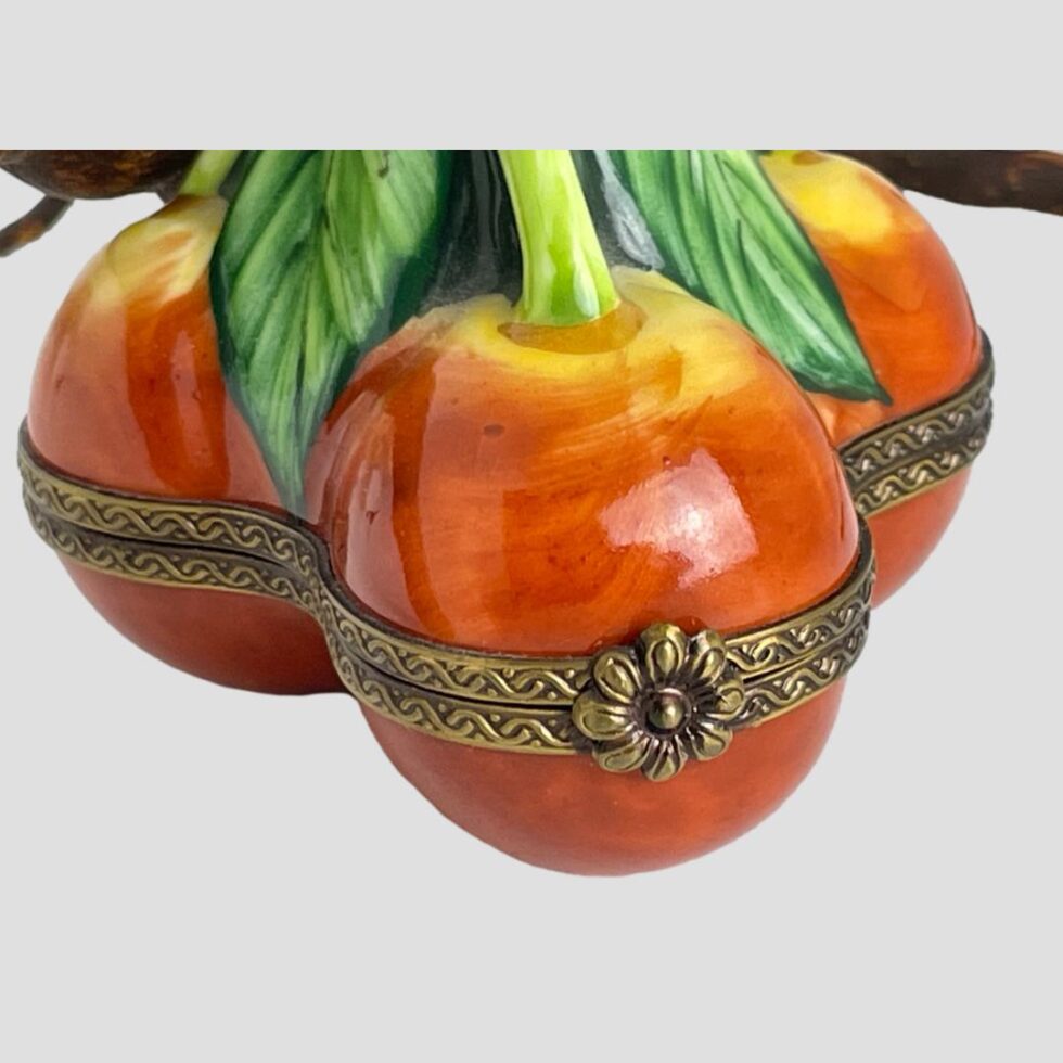 A close up of the cherries and the detailing of the hand-painting and the brass flower marking the opening point.