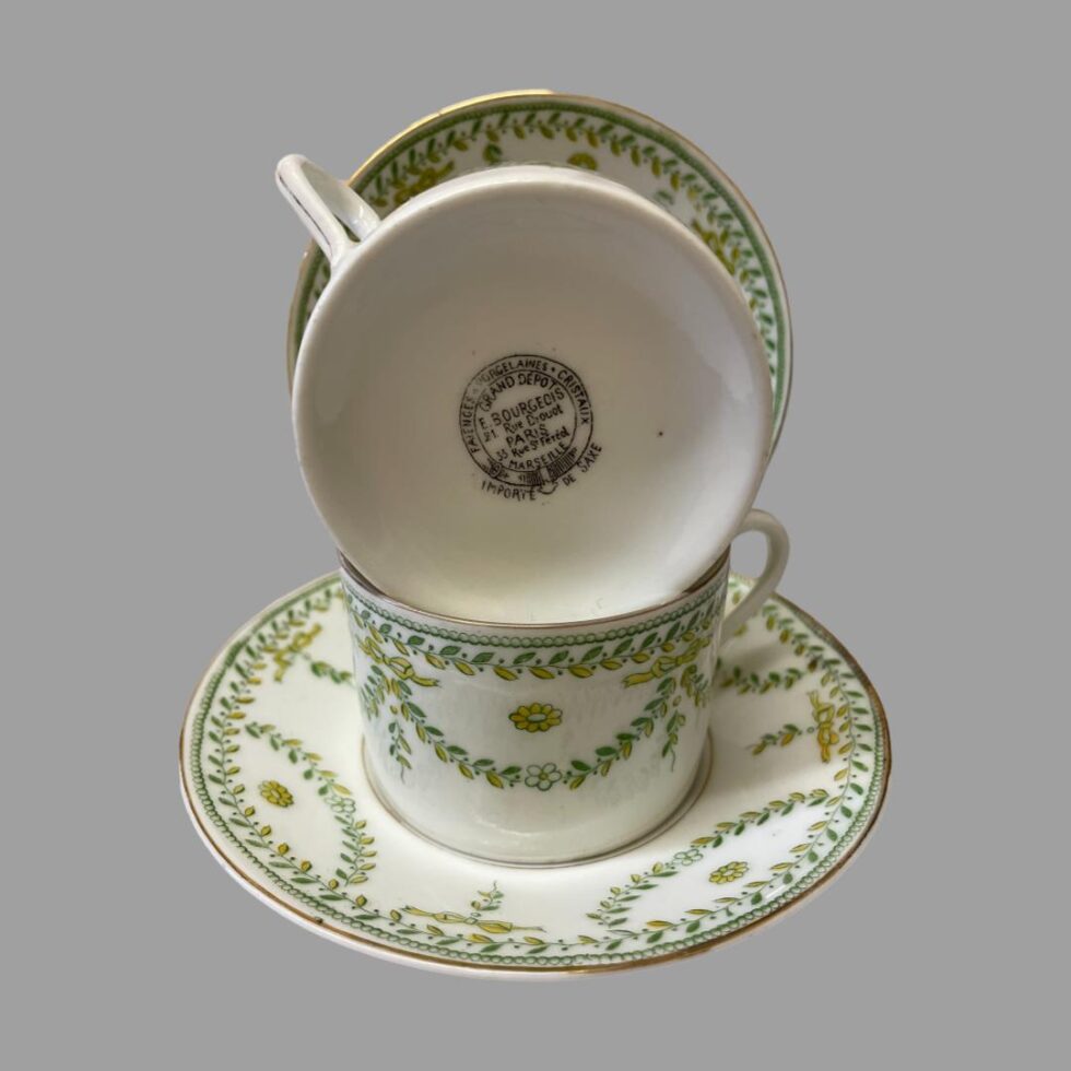Photo of antique Paris cups &saucers displayed with the base of one cup facing the camera. The cup is displayed propped on top of the other cup which is on its saucers. The other saucer is just visible behind the little tower!