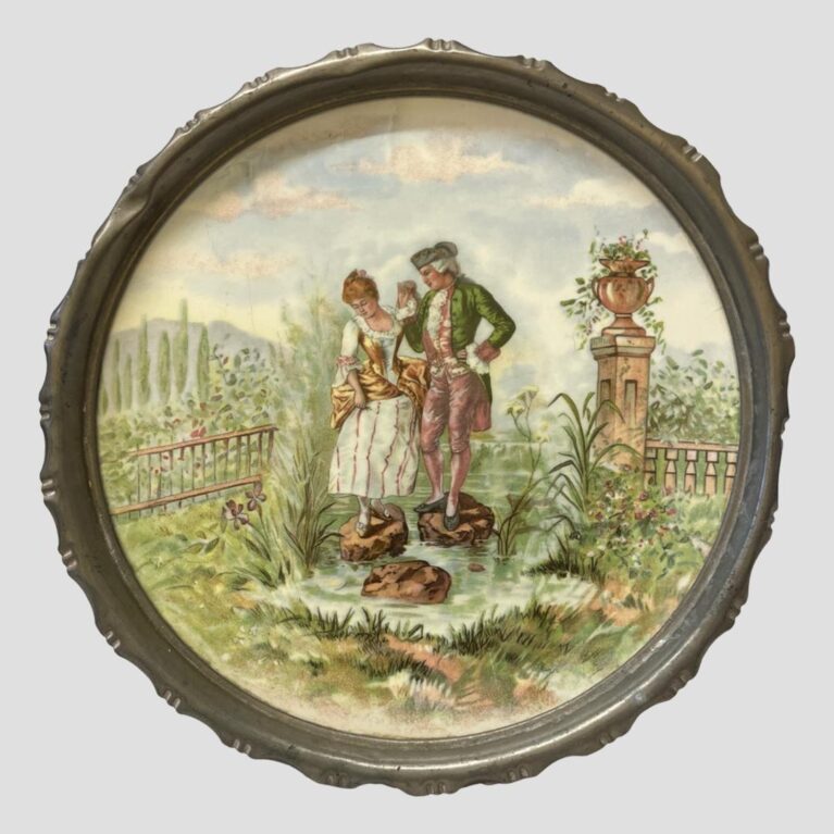 Main photo of Limoges metal rimmed tray looking straight on at the lovely romantic image at the centre. The standing on the rocks in the water may be a hidden message of risk taking or following each other to all ends. Another classical piece with many tales that can be told. The garden has several species of flora. The image is so elaborate and fine that it could be hung on the wall like a painting with the metal rim acting as a frame. Some minor scratches but overall in very good condition for a porcelain tray of this age.