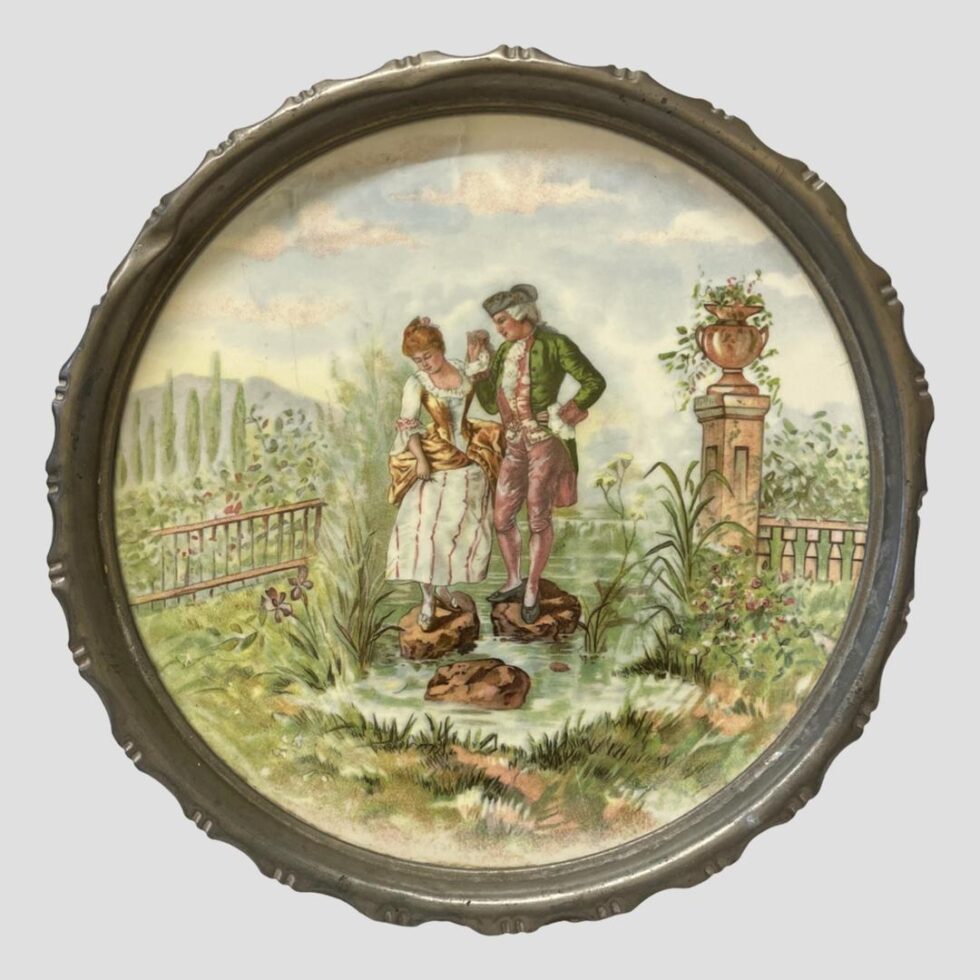 Main photo of Limoges metal rimmed tray looking straight on at the lovely romantic image at the centre. The standing on the rocks in the water may be a hidden message of risk taking or following each other to all ends. Another classical piece with many tales that can be told. The garden has several species of flora. The image is so elaborate and fine that it could be hung on the wall like a painting with the metal rim acting as a frame. Some minor scratches but overall in very good condition for a porcelain tray of this age.