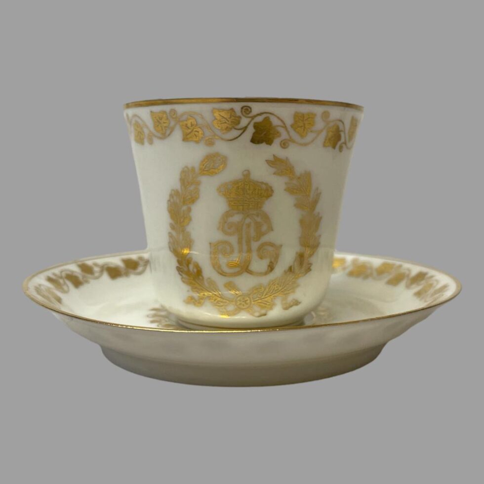 Photo of antique Sêvres Cup &Saucer this time with the cup on top of the saucer with monogrammed side on display. The saucer has a fairly high lip assume to catch any spills