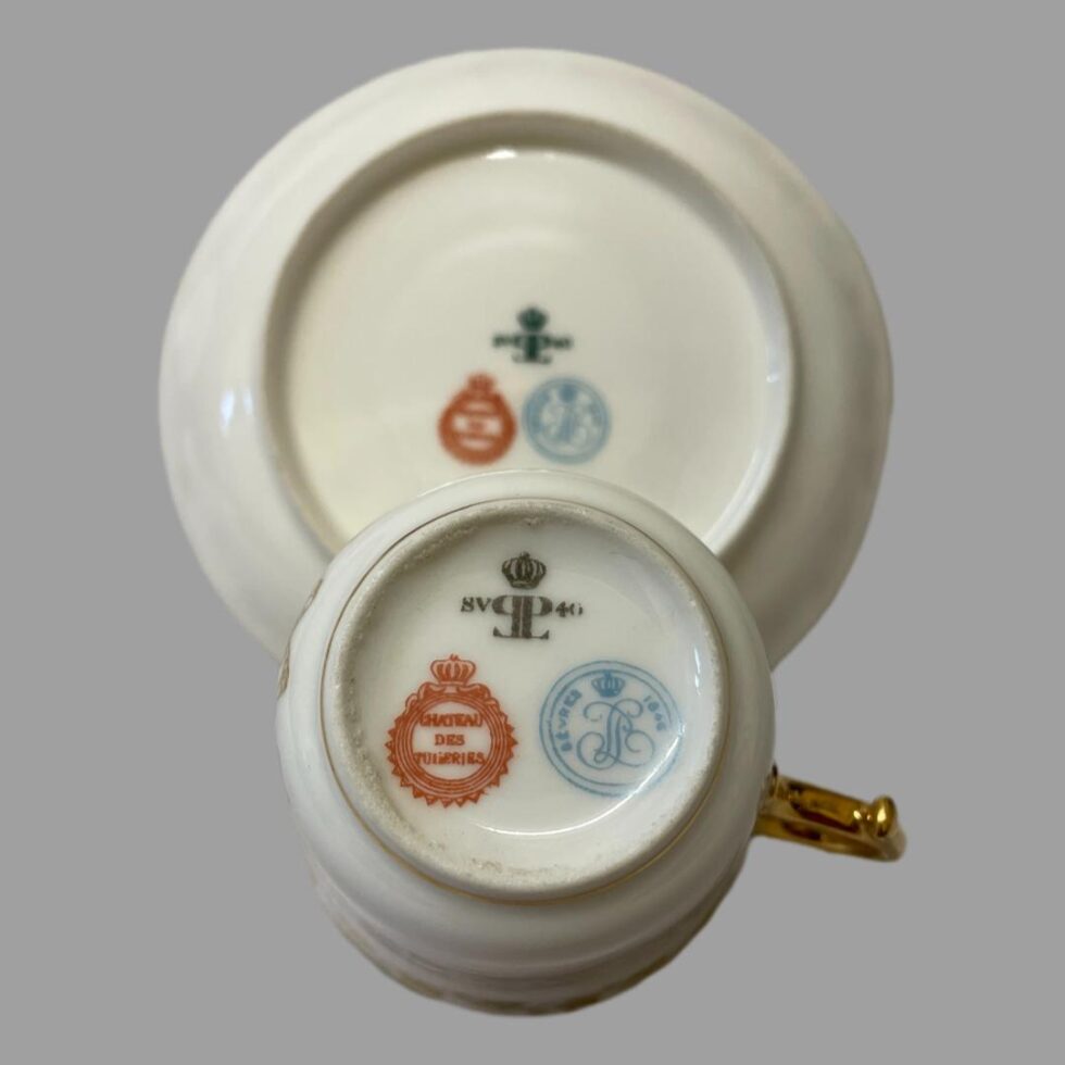 Photo of the base of both the cup and saucer showing the 3 different coloured stamps to each. Chateau des Tuileries in red, Sêvres 1846 in blue and SV 40 with crown in black. The cup is in the foreground and the saucer is upright at the back.