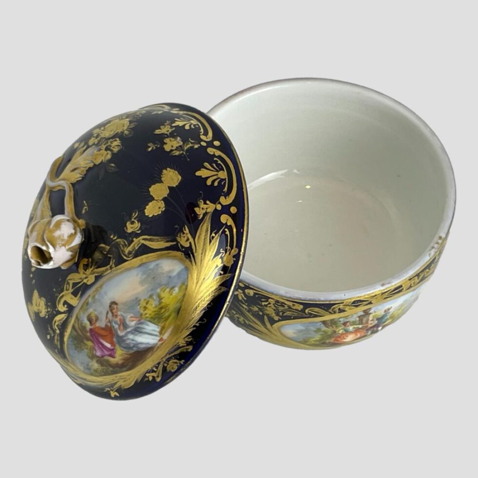 Photo of small Meissen lidded pot with the lid ridded and propped up to the left side of pot base. The inside is very clean white porcelain in very good condition.