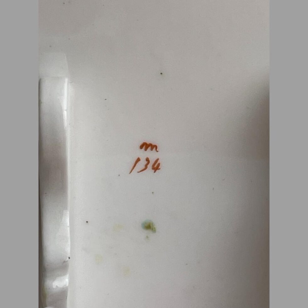 Close up photo of the m134 mark in red on the back of one of the porcelain pictures.