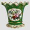 Main photo of Pairs scallop edged vase displayed with the decorative floral window side on show. The base colour of the vase is quite a breath taking shade of green - could be called green turquoise. The 'window' with flowers has a white background and there is a mixed bunch of flowers here in pink, blue, red, yellow and purple. Lovely gilt work extends over all the green turquoise area with dots and swirls. The base is white and moulded shape like sea froth with some gilt work. The top of the vase flutes outward with scalloped edge. The vase is in lovely condition but for the gilt wear around the rim which is quite extensive but could easily be touched up by someone with steady hands. Very pretty vase with or without flowers.