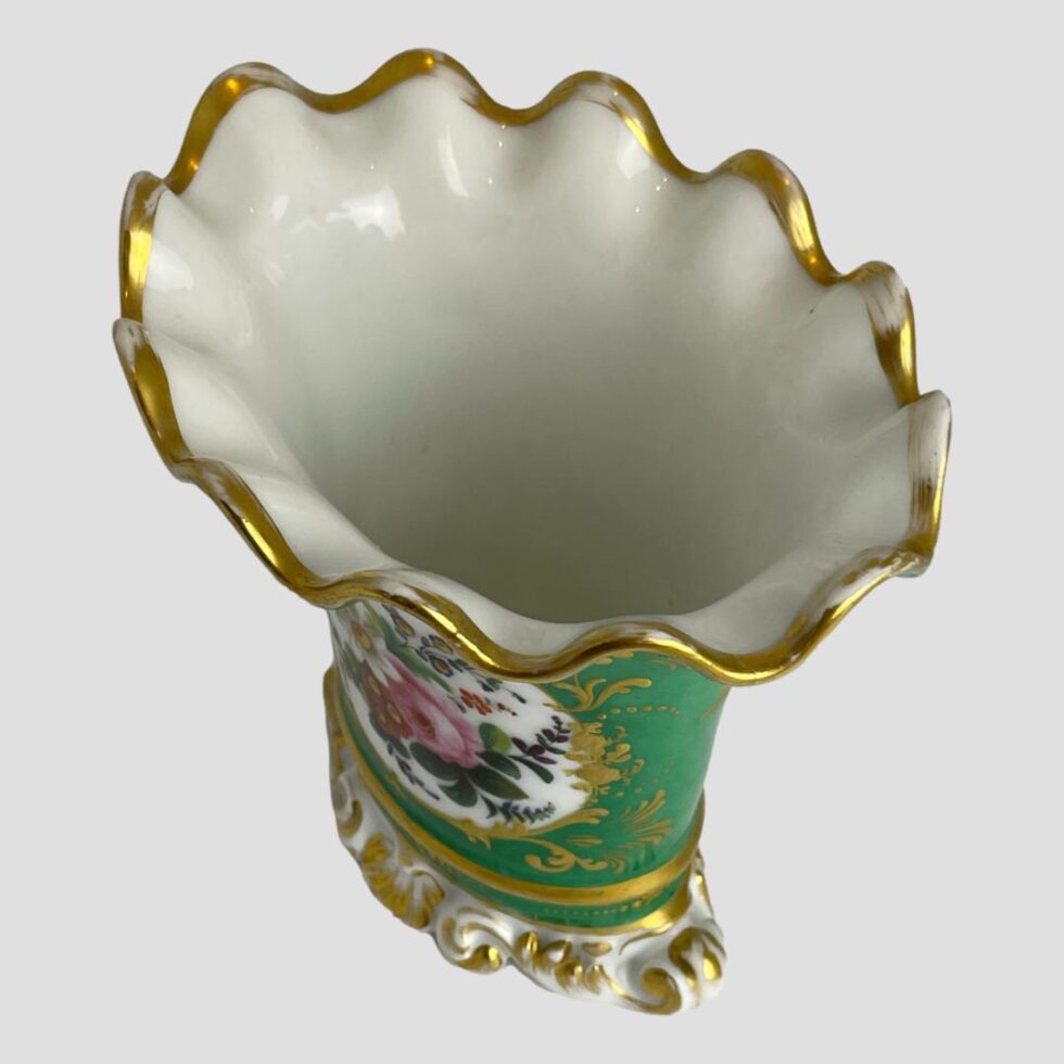 Photo looking into the mouth of the vase from above. The fluted scallop edged top is diagonally across the photo with one end in the top left and other bottom right. The wear to the gilt is clearly visible here.