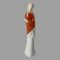 Main photo of Royal Doulton teenager figure displayed forward facing and from an eye level. This is a tall and slender teenager in a dark orange shawl and long white pleated skirt that covers her feet. The shawl is wrapped around and she is holding her right arm above the elbow with her left hand and her right hand crosses over below to her left hip - almost in a cuddle of self. She has pale blonde hair in bunched plaits and a white hair band with blue edges. Very dreamy looking facial expression.