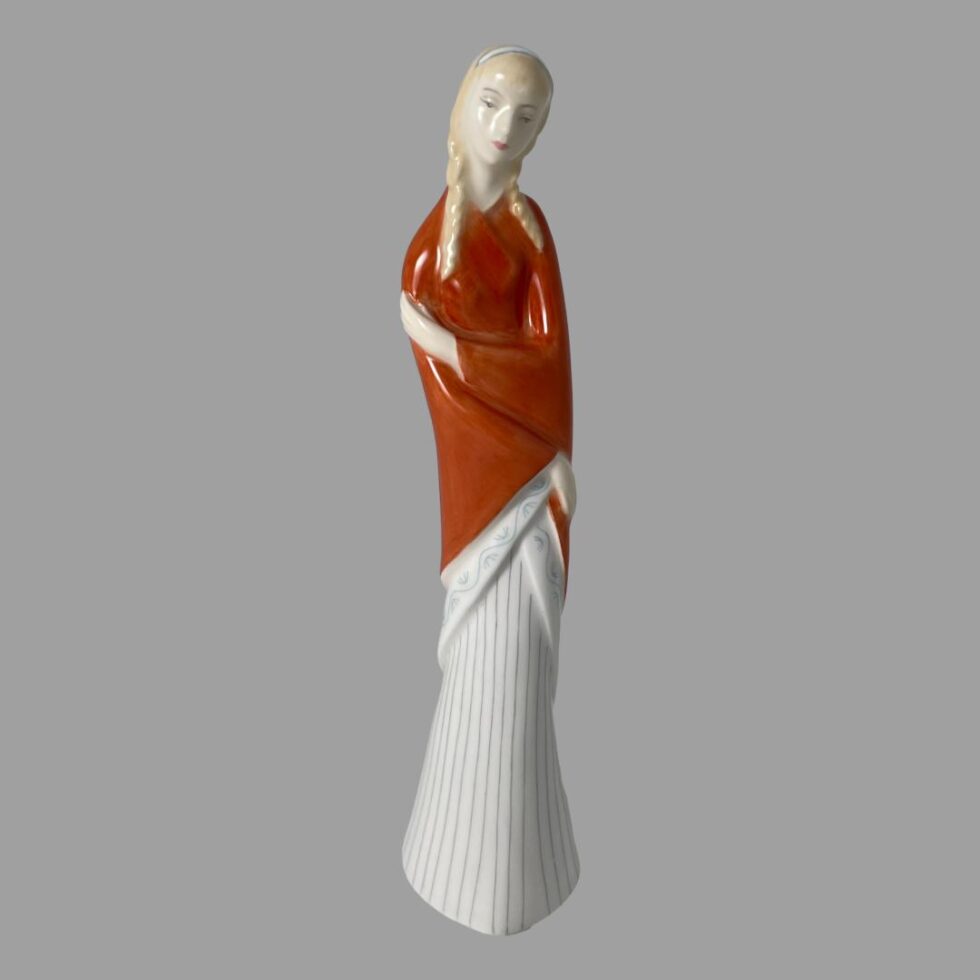 Main photo of Royal Doulton teenager figure displayed forward facing and from an eye level. This is a tall and slender teenager in a dark orange shawl and long white pleated skirt that covers her feet. The shawl is wrapped around and she is holding her right arm above the elbow with her left hand and her right hand crosses over below to her left hip - almost in a cuddle of self. She has pale blonde hair in bunched plaits and a white hair band with blue edges. Very dreamy looking facial expression.