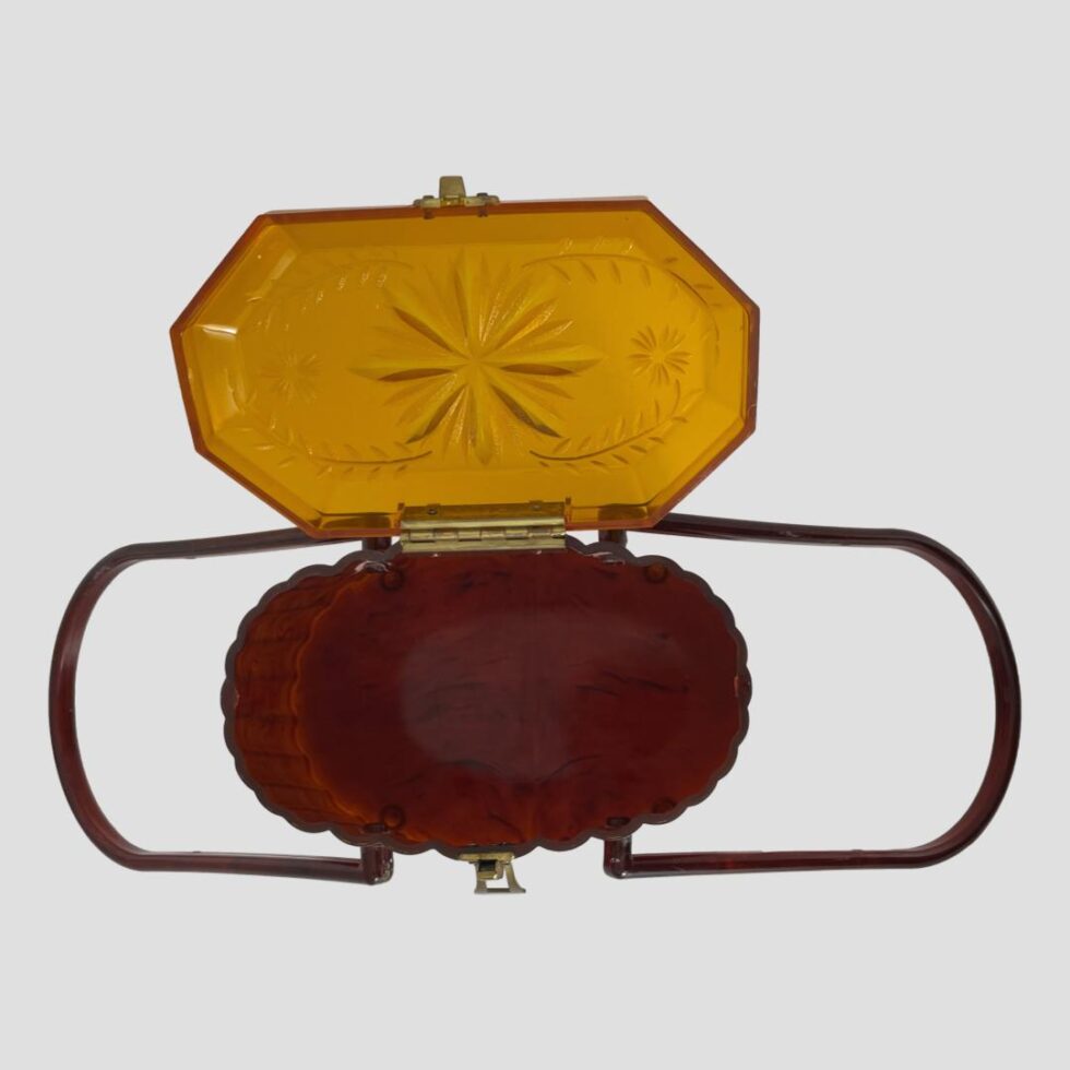 Photo looking straight down at the top of the acetate purse which has the handles down to the left and right and the lid open.