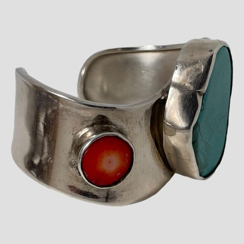 Photo of wavy Mexican cuff displayed on a flat surface with the front facing right showing the other coral piece.