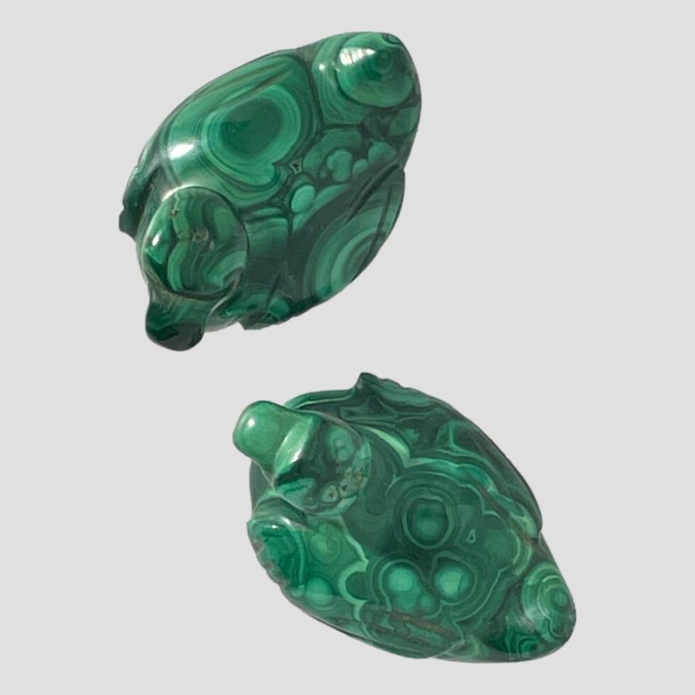 Photo looking straight down at the 2 ducks which are side by side with heads pointing inwards towards each other. One is at top of photo and other below. You can see that the quality of the malachite used in creating these pieces is very high grade.