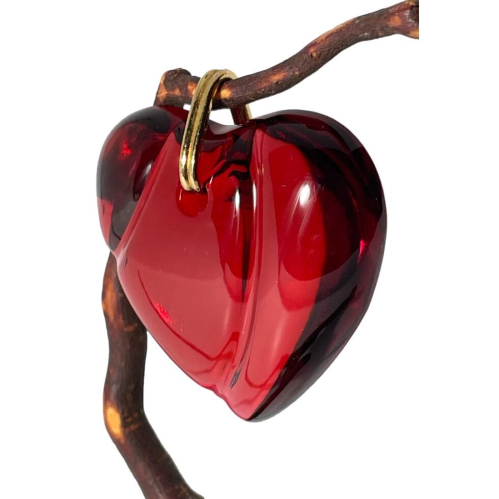 Photo of the Baccarat crystal heart pendant still displayed on a thin twig this time in close up with the front facing towards the left partially showing the depth.