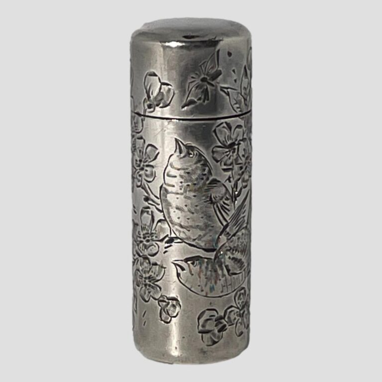 Main photo of c1888 silver scent bottle seen from an eye level with the opening front side in the foreground. The engraved decoration on this side shows 2 birds perched on a branch of cherry in blossom. The bird in the background is looking up at a butterfly on the front of the lid and the other is looking towards the left. Very detailed fine engraving to birds, flora and butterfly. These scent bottles were most likely used by ladies or even gentlemen when travelling. It is nice and compact with the original glass stopper inside which closed tightly and the lid of course with good closure.