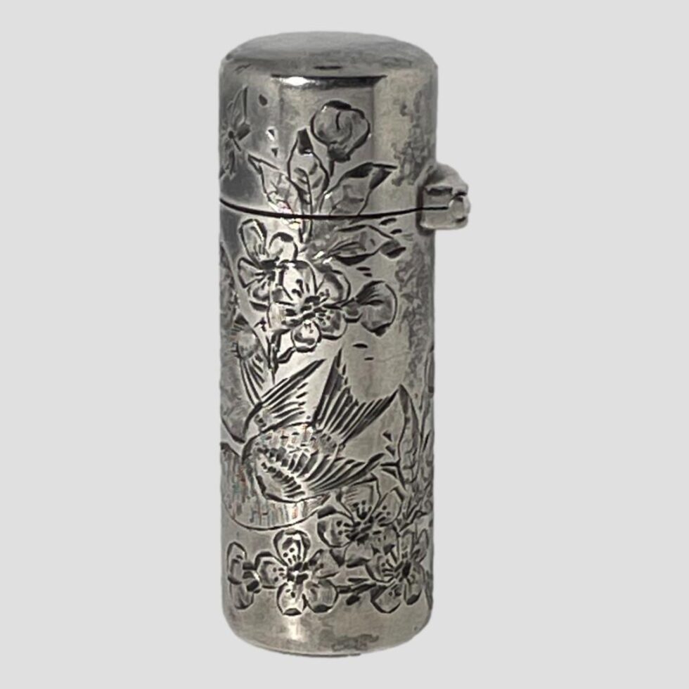Photo of antique silver scent bottle this time with the opening front side facing extreme left. The sturdy hinge area is visible to the right. The engraving is a continuation from the main photo and shows the body of the second bird which is in the foreground in main photo.