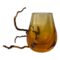 Main photo of Whitefriars amber hambone vase seen from an eye level and displayed with wider side forward facing. The vase called hambone as it resembles a ham bone. It has a thick rounded base with the orange colour darkest here before graduating to lighter shade at top. There is a dried twig behind the vase partially sticking out on the left.
