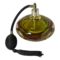 Main photo of modern Murano perfume atomiser displayed seen from a slightly raised angle looking diagonally downward. The glass bottle has 4 flat sides and is mainly a yellow/green with clear base and an amber sommerso inclusion. The black spray atomiser is to the left with the puffer ball and tassel in the left foreground. We are looking at the bottle with a none flat side in the foreground.