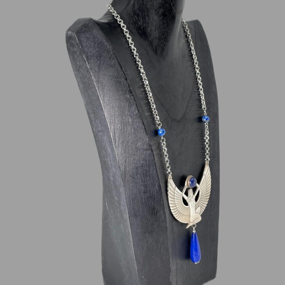 Photo of the Egyptian revival Isis necklace still displayted on a black wooden display stand this time with the necklace front facing towards the right.