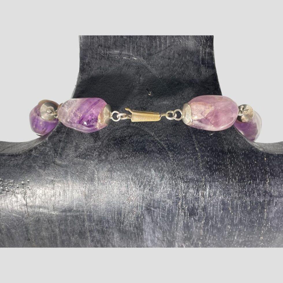Photo of the clasp area of the necklace which has some yellowing especially to the clasp. As the large beads are heavy, they are threaded on metal posts which are then attached with short chain to next. (String would not offer the same security.