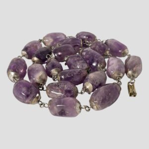 Main photo of the large amethyst beads necklace displayed on a flat surface and coiled like a snake. None of the beads are identical in size or colour giving this necklace an added charm. Truly a statement piece & quite heavy!