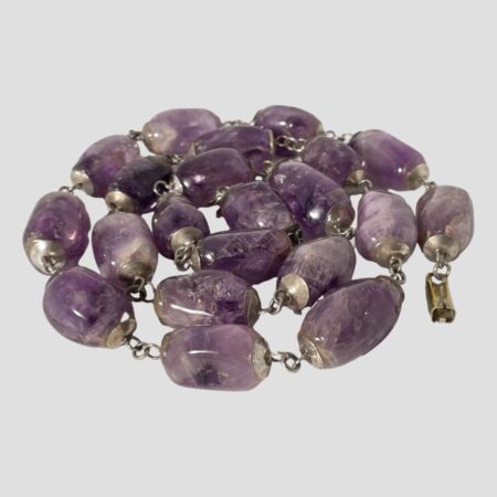 Main photo of the large amethyst beads necklace displayed on a flat surface and coiled like a snake. None of the beads are identical in size or colour giving this necklace an added charm. Truly a statement piece & quite heavy!