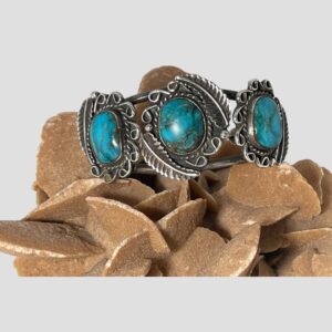 Main photo of antique Navajo cuff bracelet displayed on top of a rock of natural desert sand rose and shown with the front of bracelet facing forward.