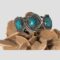 Main photo of antique Navajo cuff bracelet displayed on top of a rock of natural desert sand rose and shown with the front of bracelet facing forward.