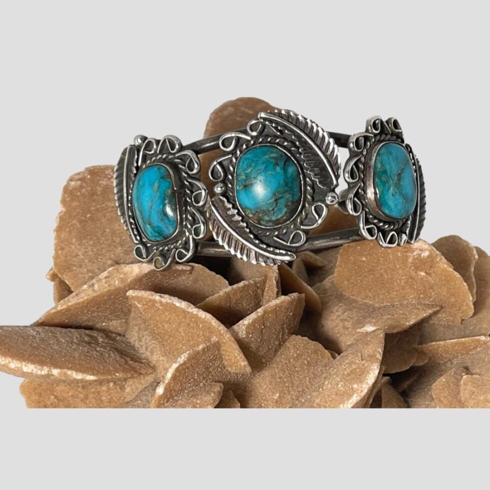 Main photo of antique Navajo cuff bracelet displayed on top of a rock of natural desert sand rose and shown with the front of bracelet facing forward.