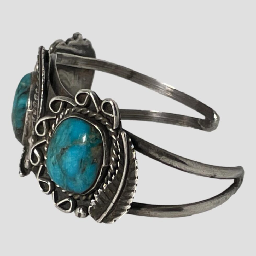 Photo of turquoise cuff bracelet displayed on a flat surface this time with the front facing left.